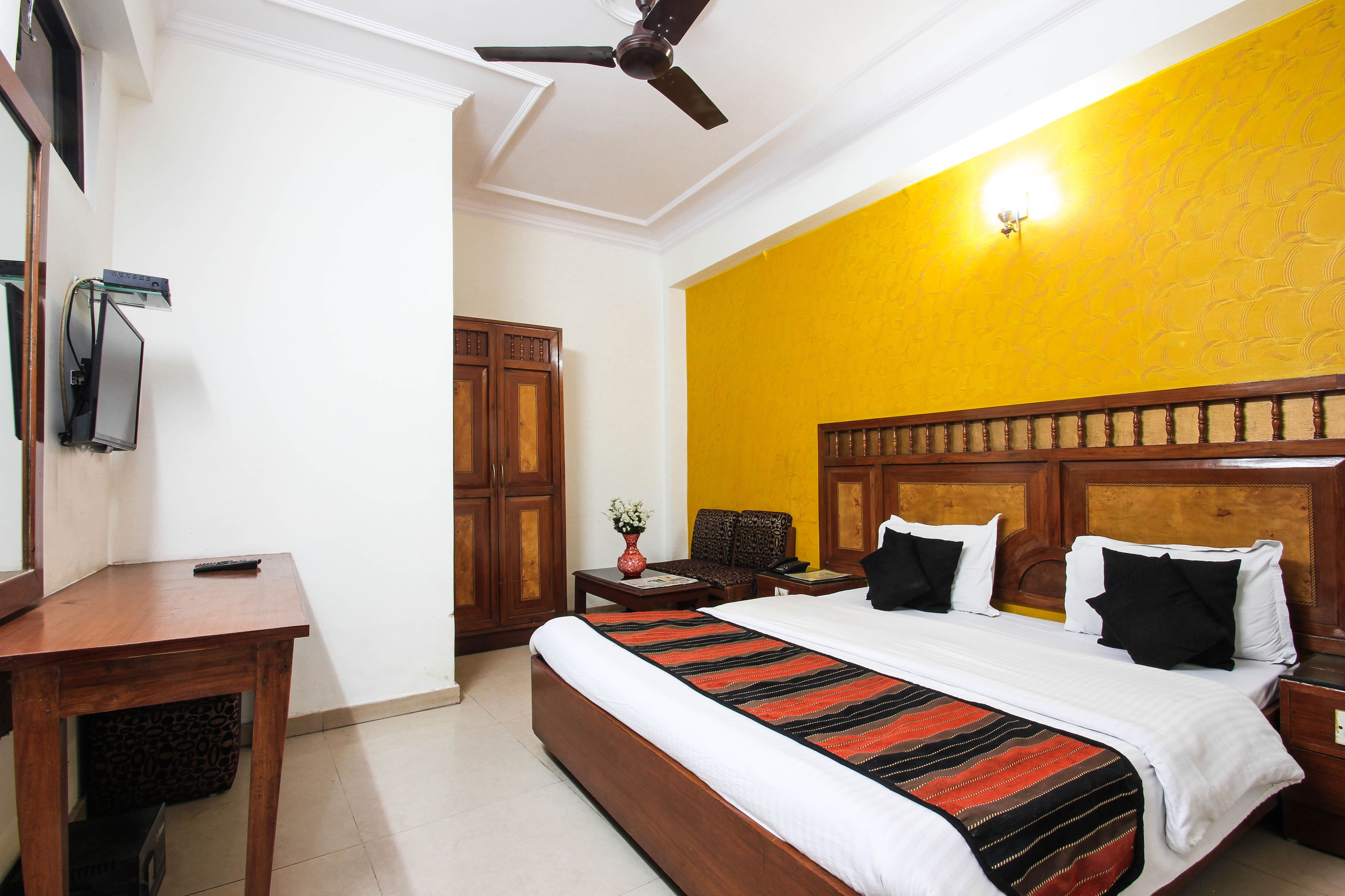 A hotel room with a bed, bedside table, nightstand, and a ceiling fan.