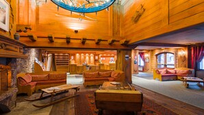 A spacious log cabin interior with multiple seating areas, a stone fireplace, and a large wooden ceiling. - Residence  Le Cristal d'Argentière (Chamonix-Mont-Blanc)
