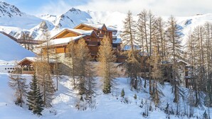 A snow-covered mountain lodge with multiple wooden buildings, surrounded by snow-covered trees and mountains. - Résidence Lagrange Vacances Aspen (La Plagne-Tarentaise)
