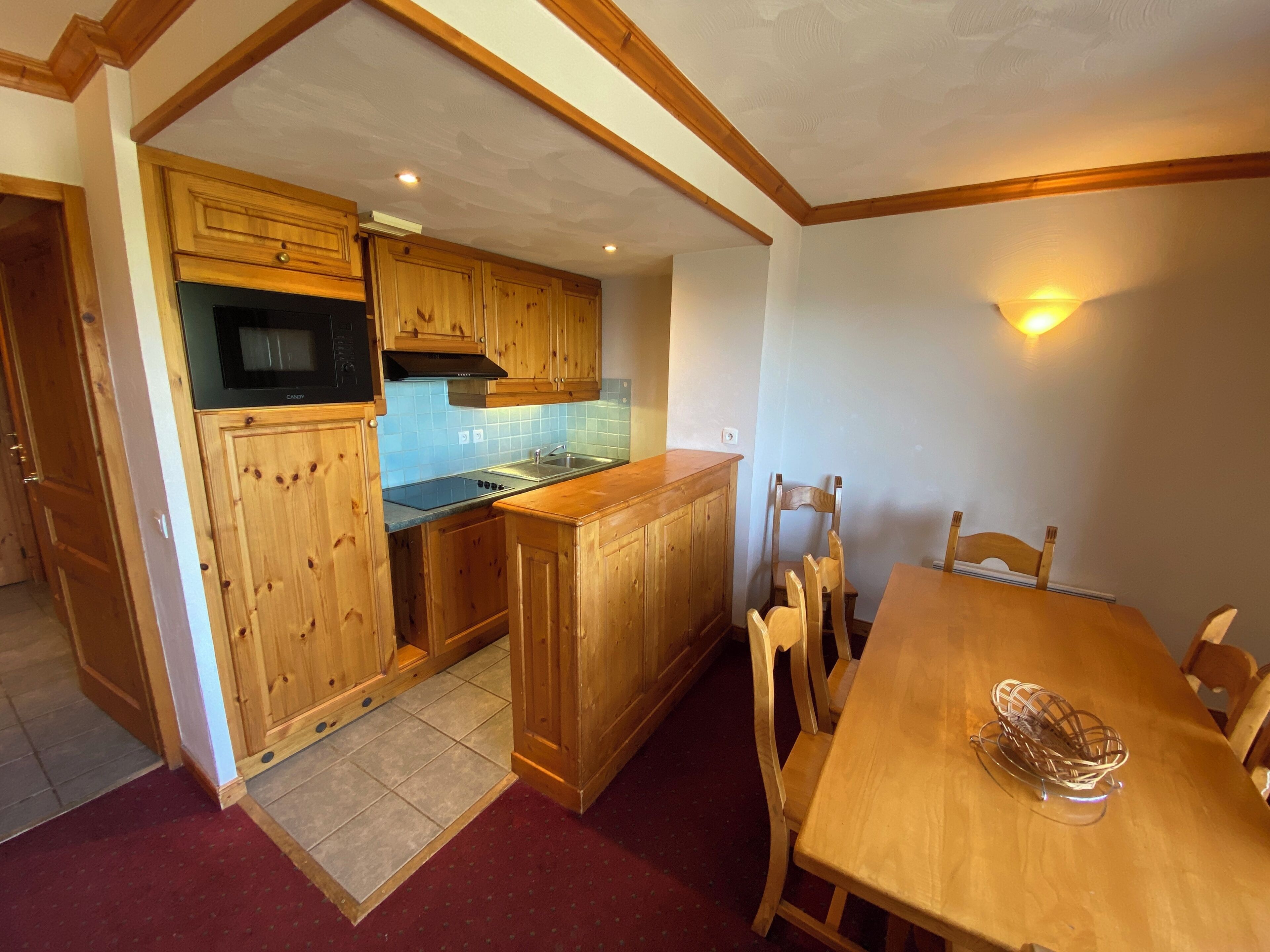 Une cuisine avec des meubles de rangement en bois, une cuisinière et un coin repas comprenant une table et des chaises.