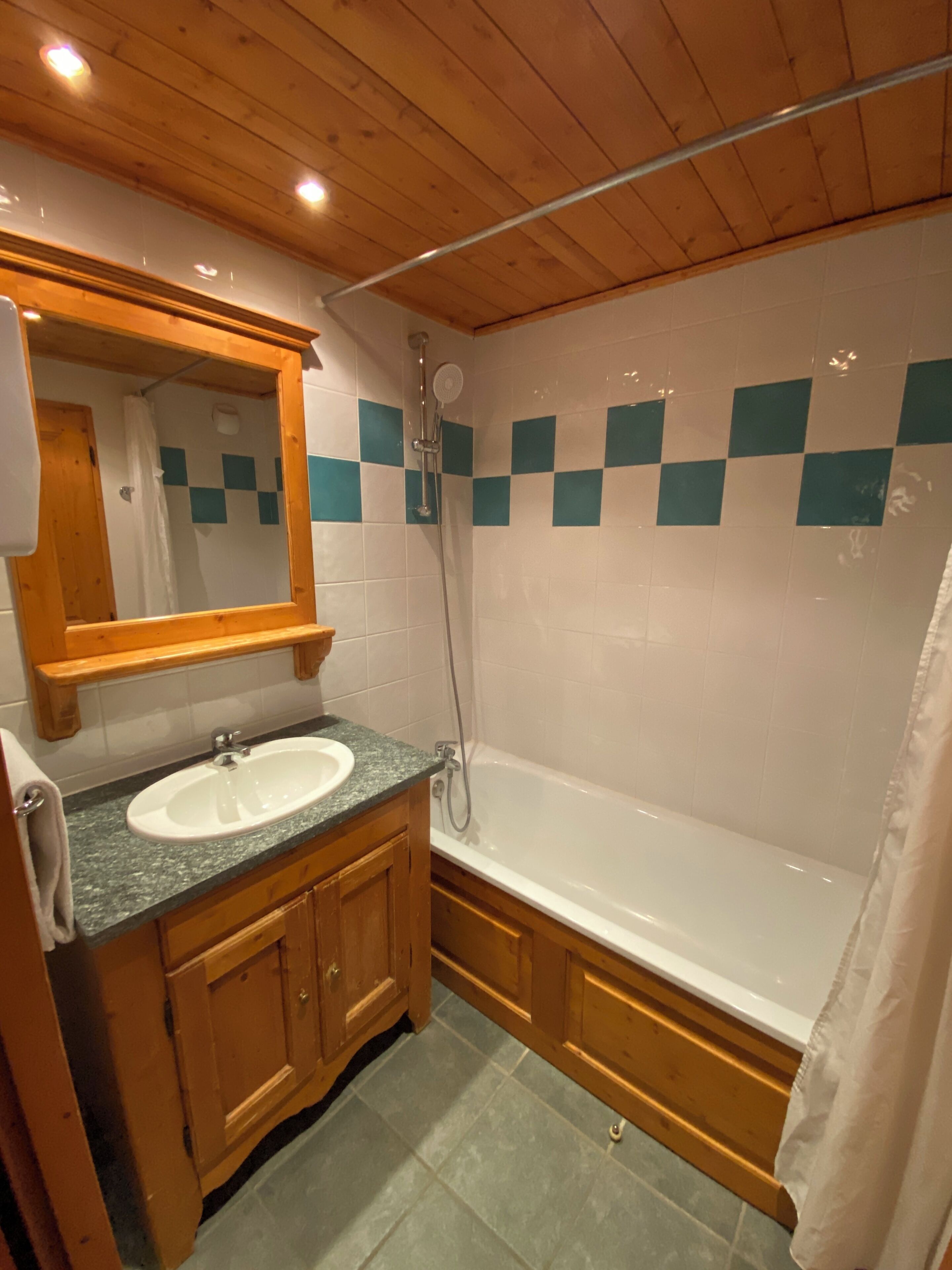 A bathroom with a wooden vanity, a sink, a mirror, a shower, and a bathtub.