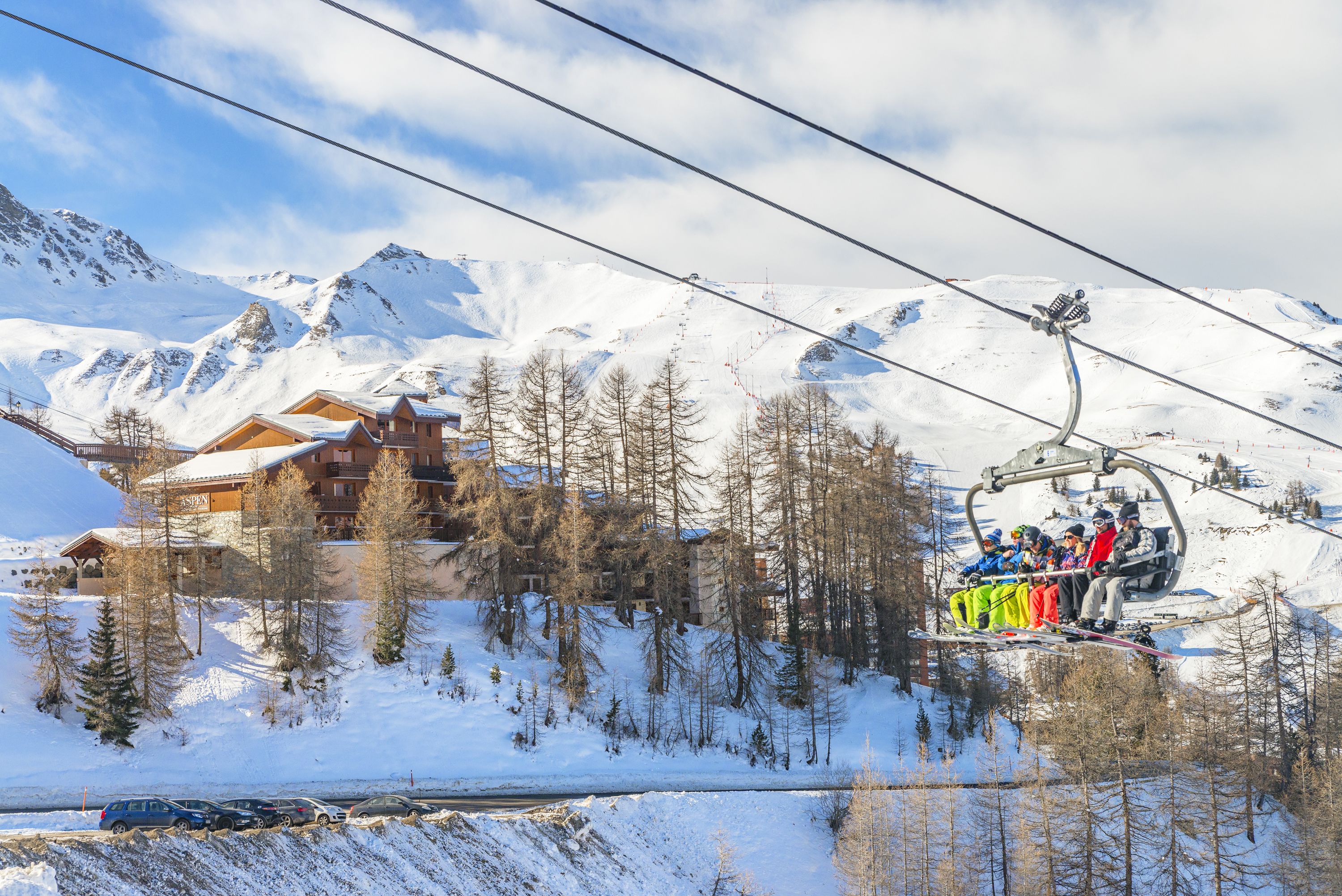 Eine Seilbahn mit Fahrgästen, eine Berghütte und schneebedeckte Berge.