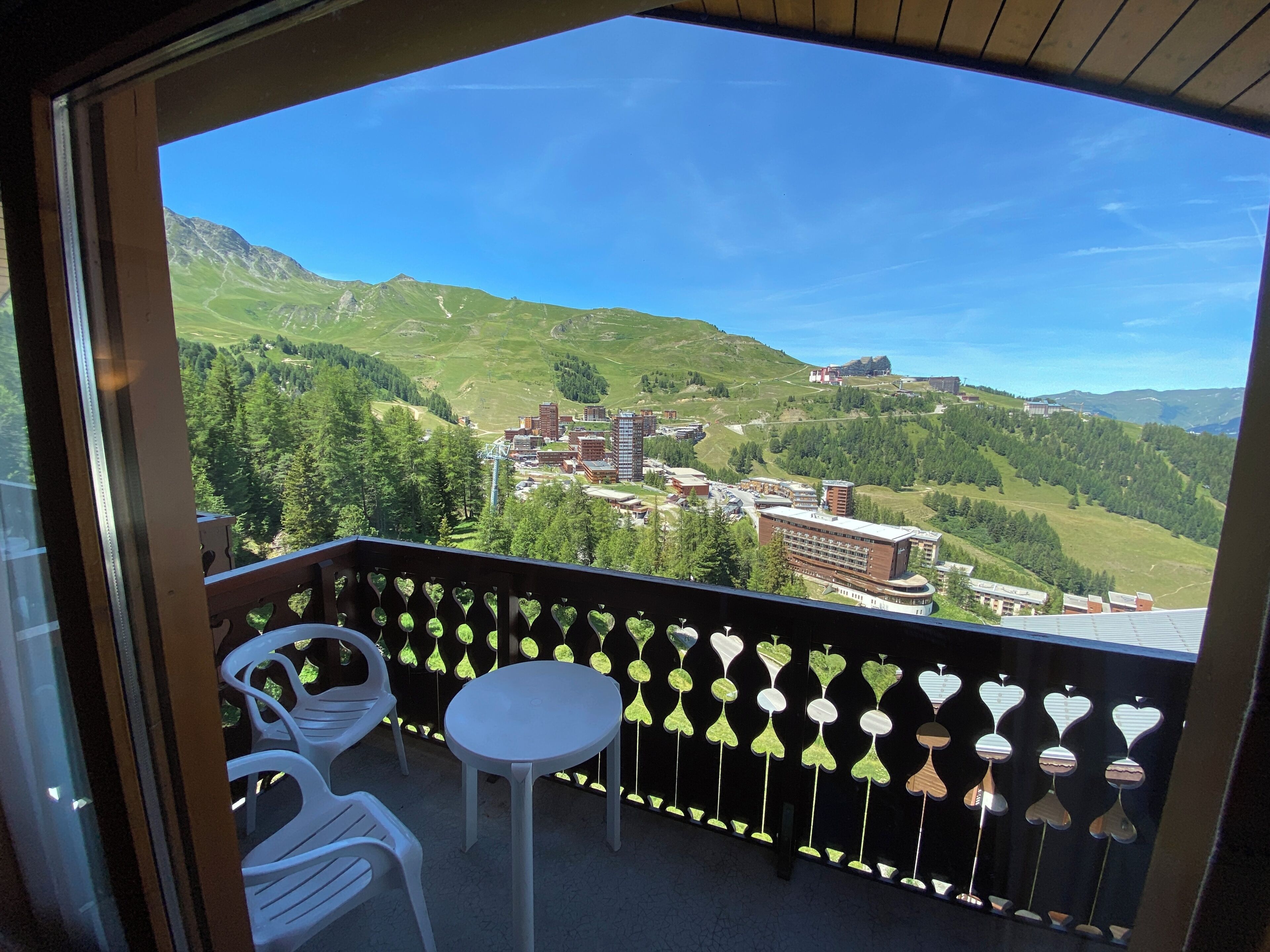 Un balcon offrant une vue sur un paysage montagneux, avec des bâtiments et de la végétation.