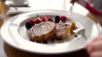 A plate of pancakes with syrup and berries.