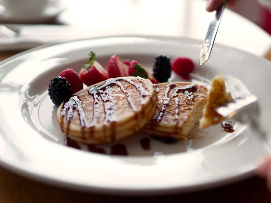 A plate of pancakes with syrup and berries.