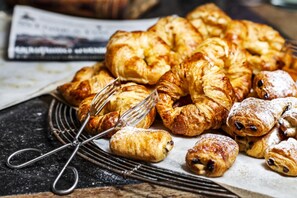 A variety of pastries, including croissants and small rolls, arranged on a wire cooling rack with a newspaper in the background. - Radisson Blu Hotel & Spa, Sligo (Sligo)