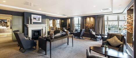 A modern hotel lobby with a fireplace, comfortable seating, and large windows offering a view.