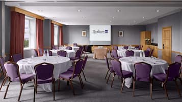 A conference room with round tables, purple chairs, and a presentation screen.