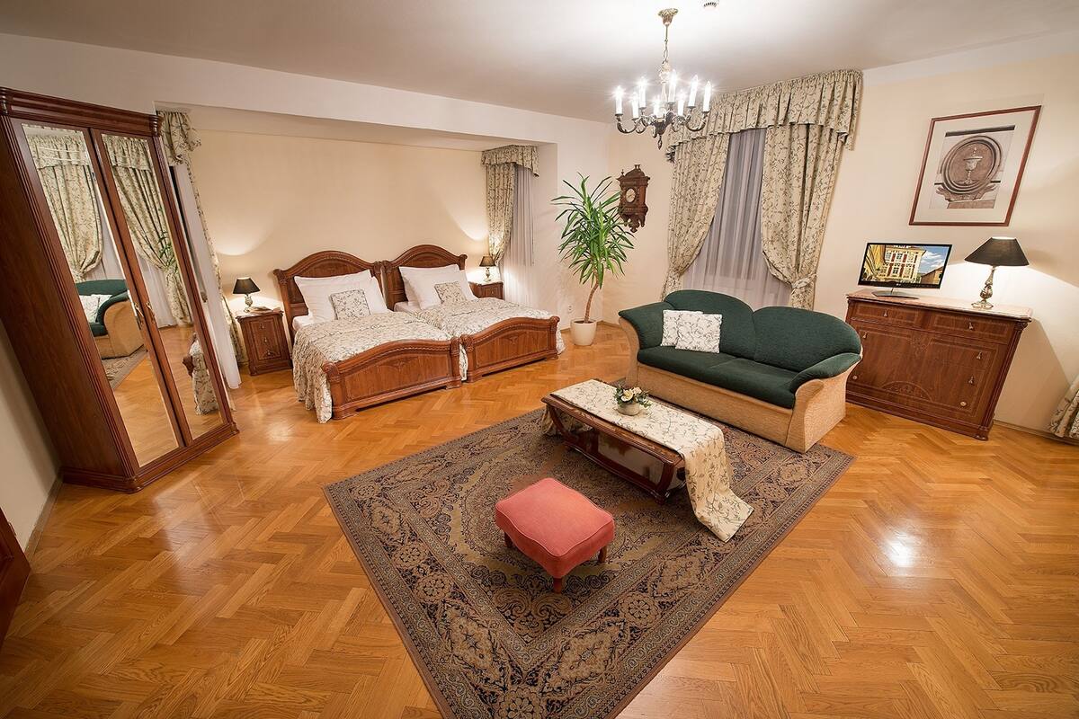 A well-lit room with a bed, a sofa, a small table, and a mirror.