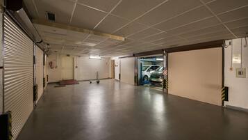Ett rent, tomt parkeringsgarage med stängda garageportar, en brandsläckare och en tydligt markerad utgångsdörr.