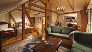 A spacious loft bedroom with a large bed, a green sofa, and a wooden coffee table. - Boutique Hotel Constans (Prague)