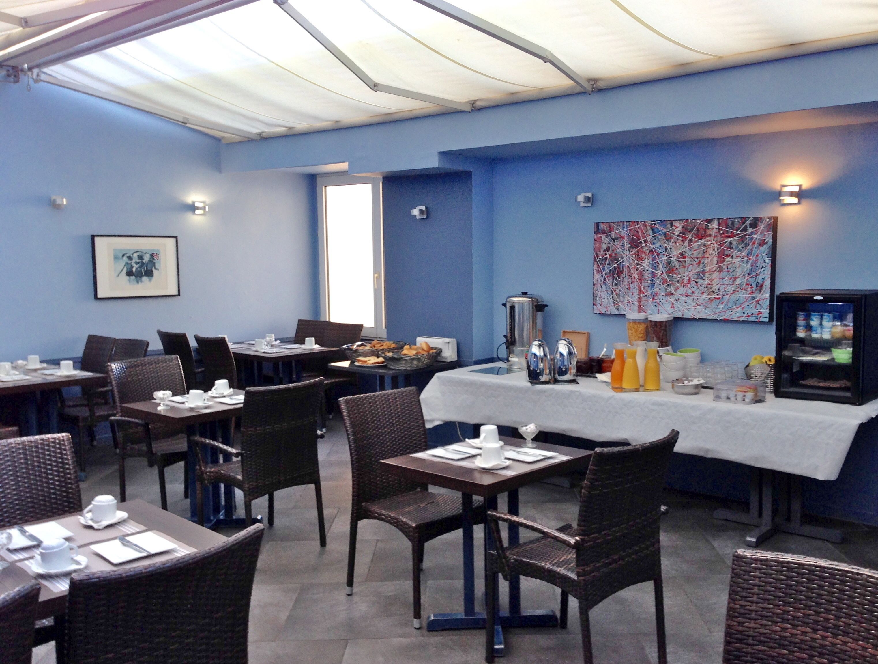 Un restaurant avec des tables et des chaises, un coin café et un réfrigérateur.