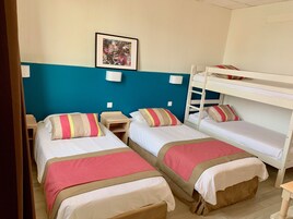 A room with two single beds, a bunk bed, and a small bedside table.