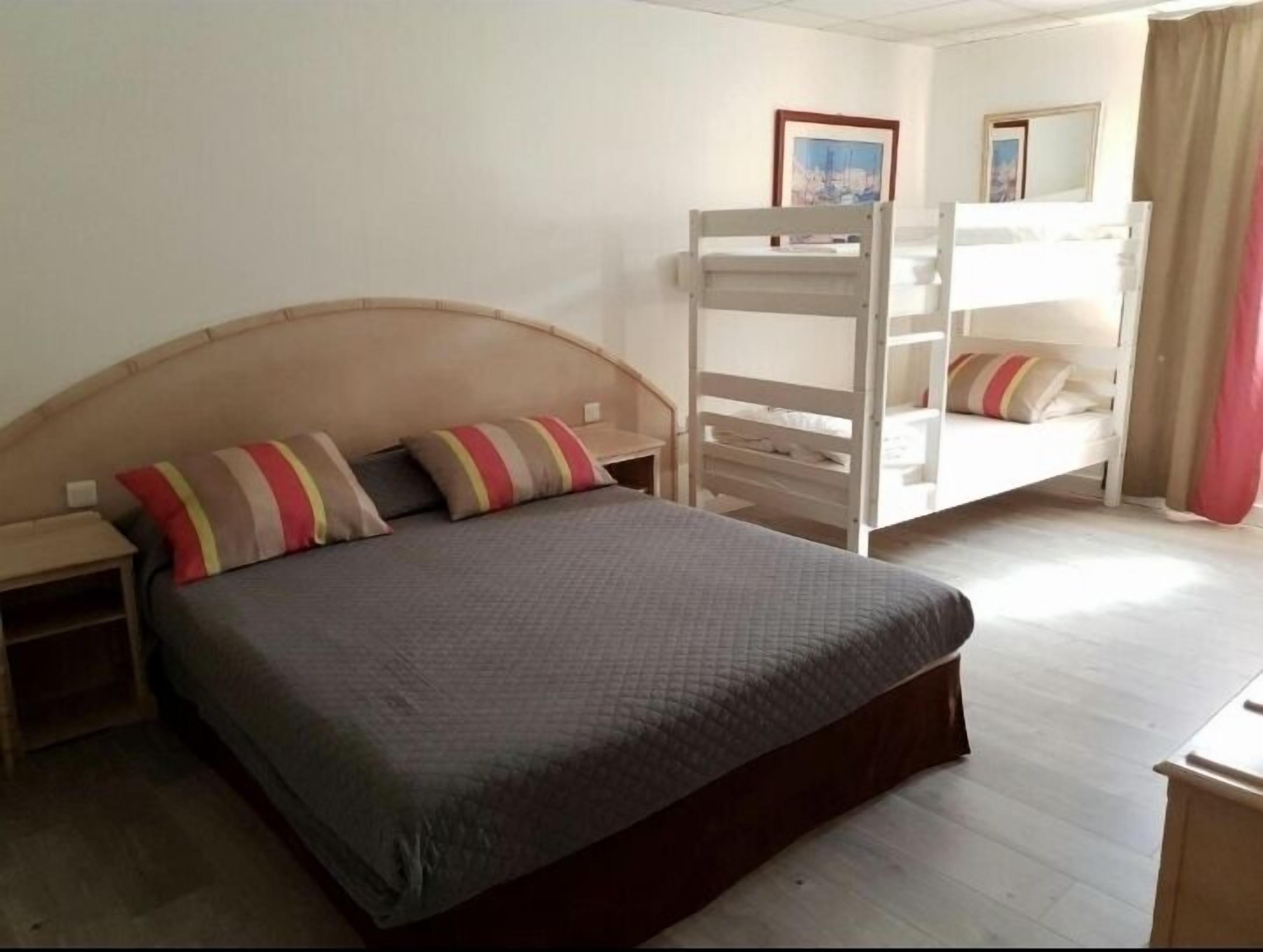 A single bed with a headboard, two bedside tables, a bunk bed, and a mirror on the wall.