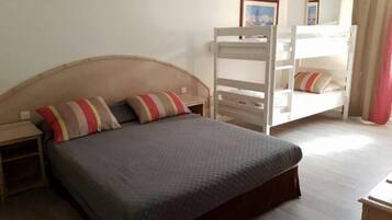 A single bed with a headboard, two bedside tables, a bunk bed, and a mirror on the wall.