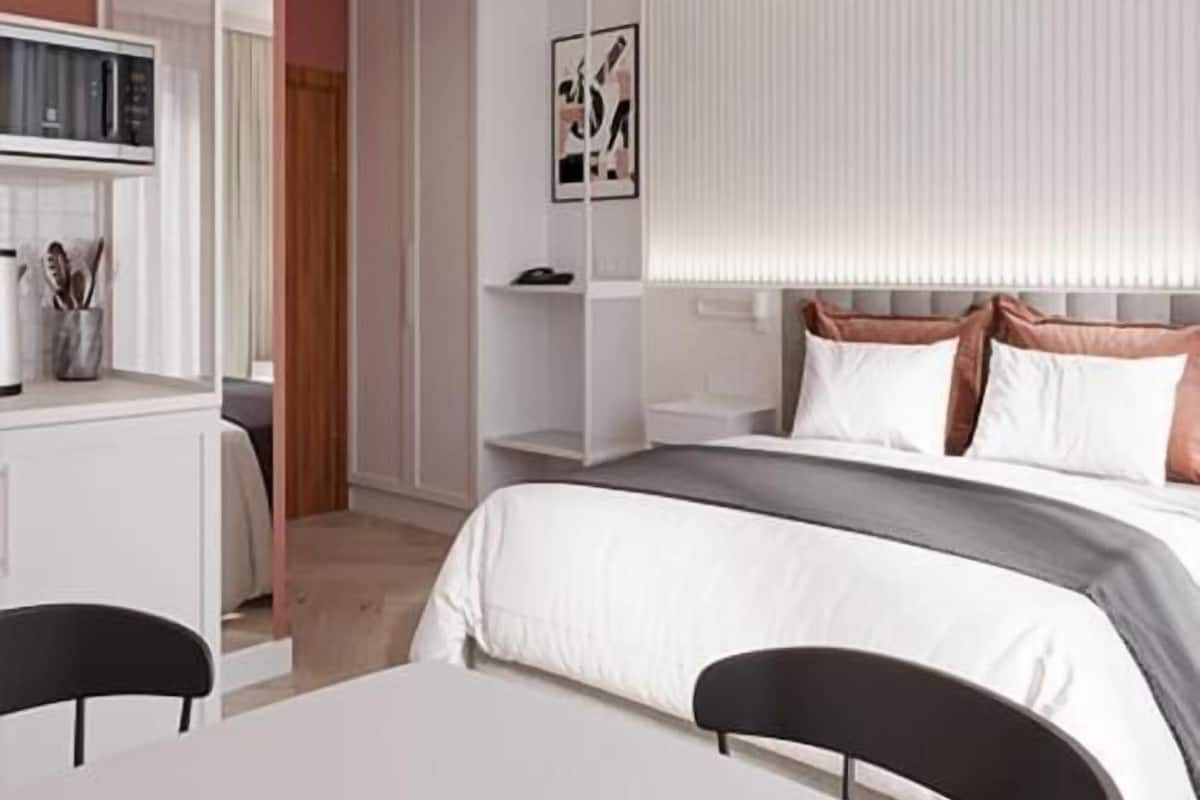 A modern bedroom with a bed, bedside table, and a small desk with a chair.