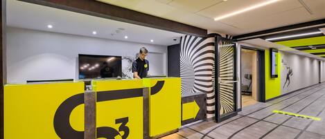 A modern reception area with a bright yellow counter, a digital screen, and a unique black and white spiral wall design.