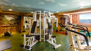 A gym with various exercise equipment, a wooden floor, and a mural on the wall. - Residence Lagrange Vacances le Village des Lapons (Hauteluce)