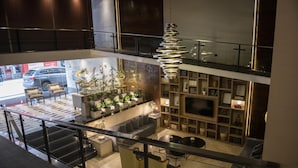 A modern interior with a sofa, chairs, a TV, and a staircase. - Grand King Hotel (Buenos Aires)