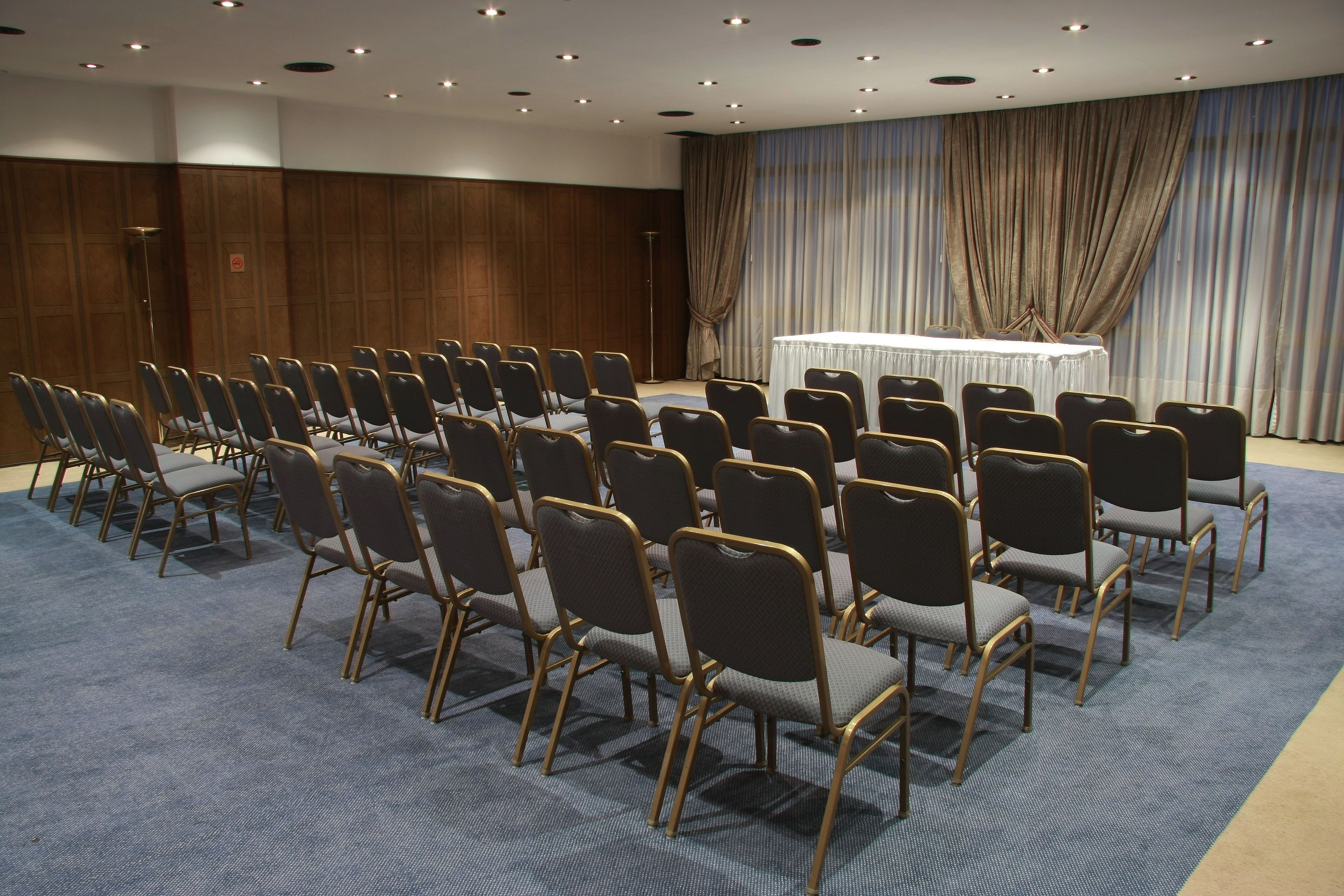 Ein Konferenzraum mit Reihen von Stühlen, einem Tisch und einer großen Stoffkulisse.