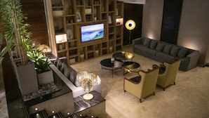 A modern living room with a television, sofa, chairs, a coffee table, and a bookshelf. - Grand King Hotel (Buenos Aires)