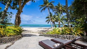 A beachside lounge area with a view of the ocean, surrounded by palm trees and tropical plants. - Pacific Resort Rarotonga (Rarotonga)