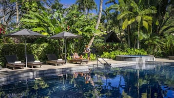 Una piscina al aire libre, sombrillas, sillones reclinables de piscina
