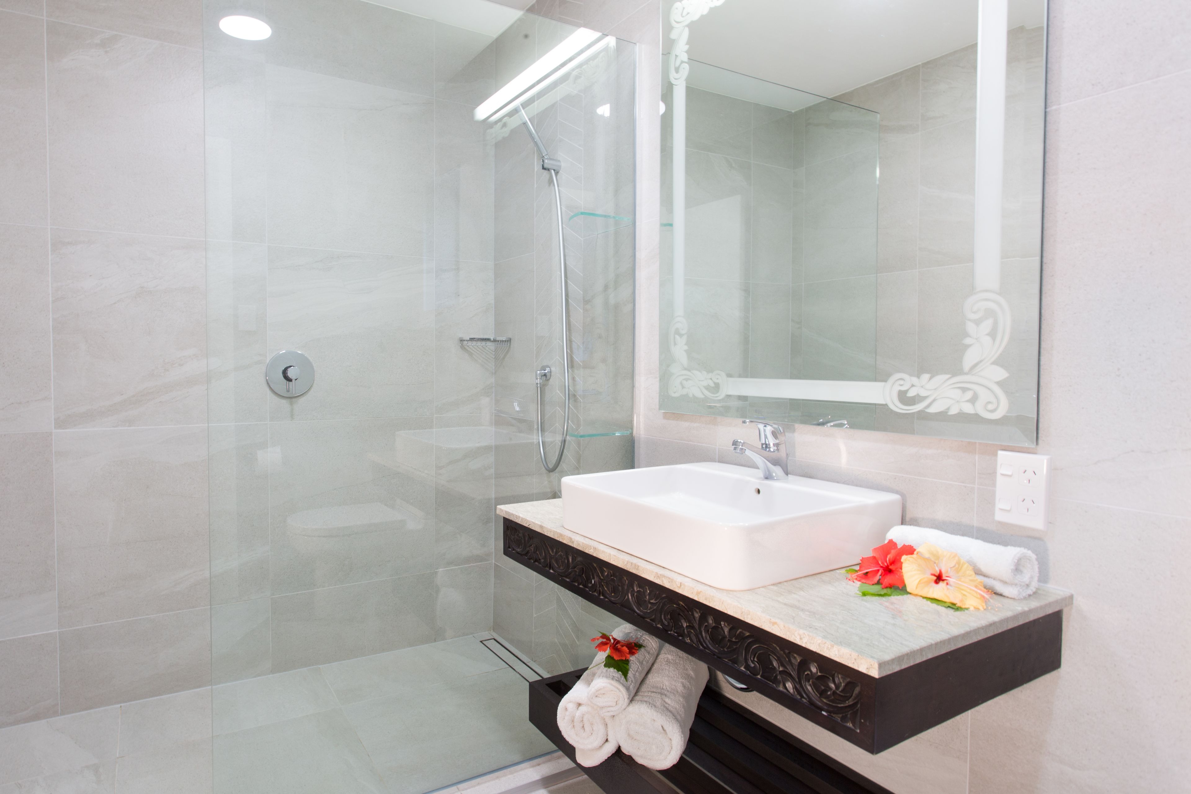 Un baño moderno con ducha envuelta en vidrio, un lavamanos blanco y una encimera de mármol.