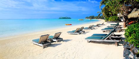 A beach with sun loungers and a clear view of the ocean.