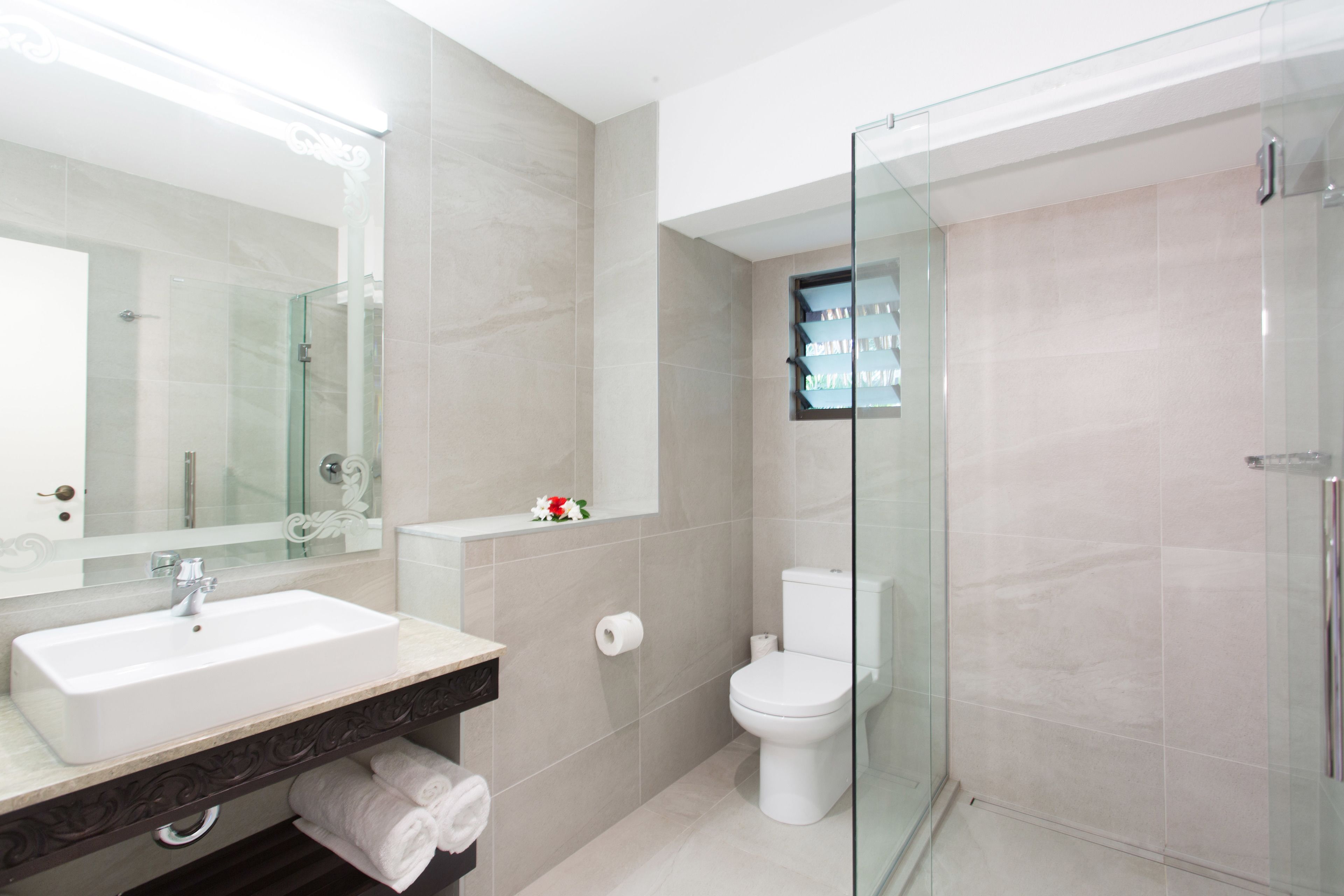 A modern bathroom with a glass shower enclosure, a white sink, and a toilet.