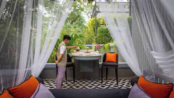 A dining area with a round table, two chairs, and a person serving.