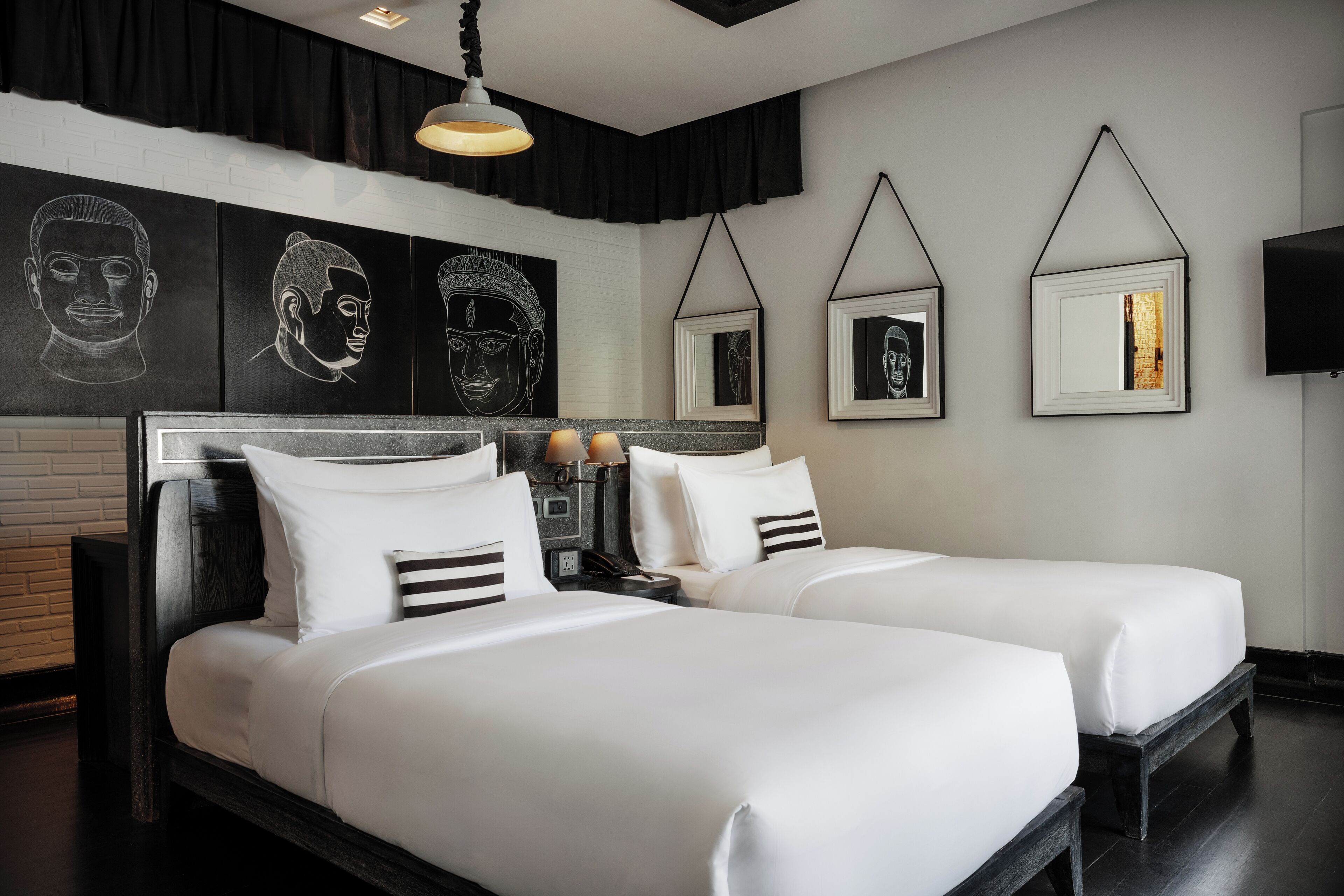 Una habitación de hotel moderna con dos camas individuales, una obra de arte grande en la pared y un televisor de pantalla plana.