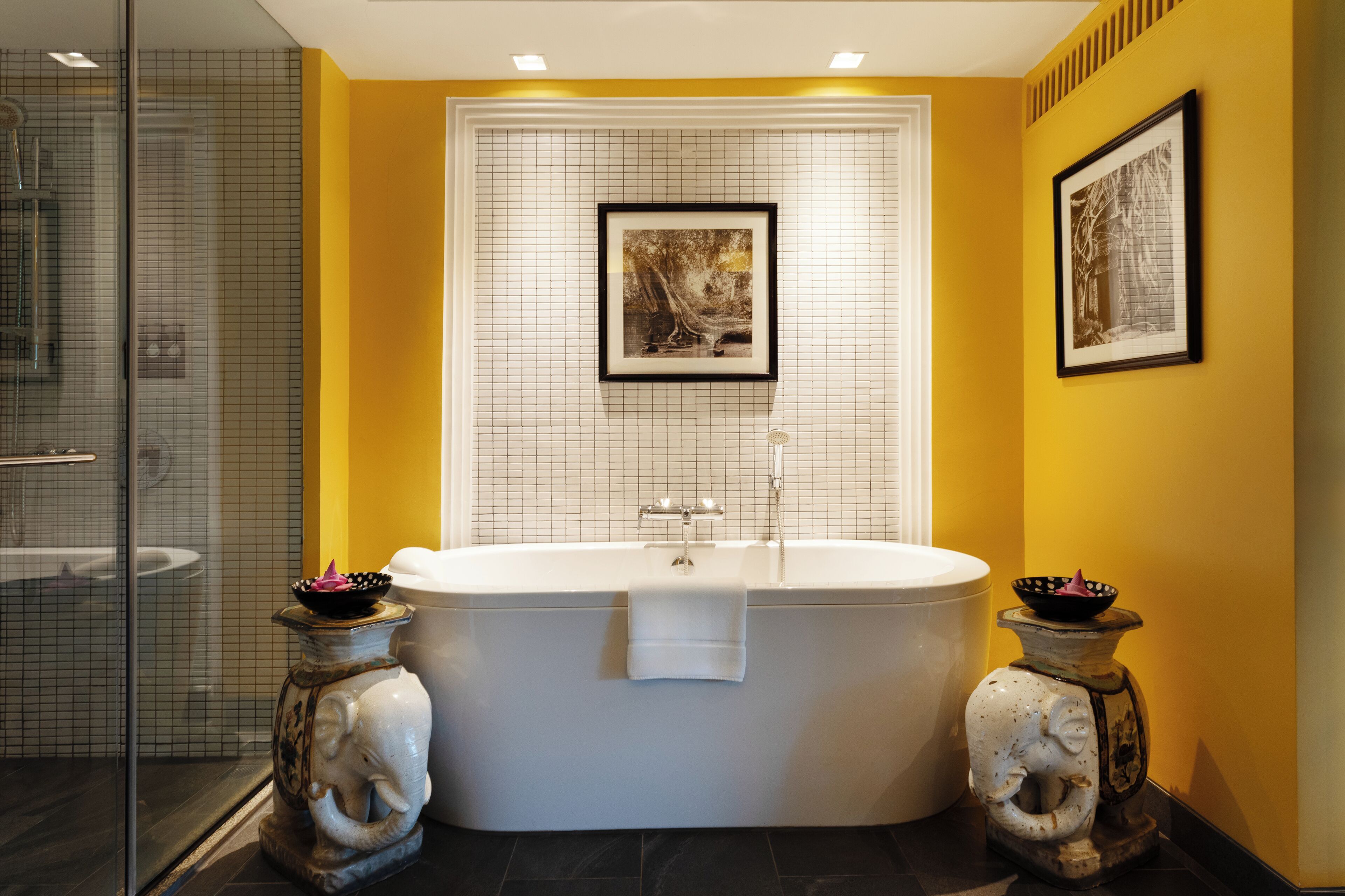 Une salle de bain moderne avec une baignoire sur pieds, une douche à l’italienne en verre et deux vases décoratifs.
