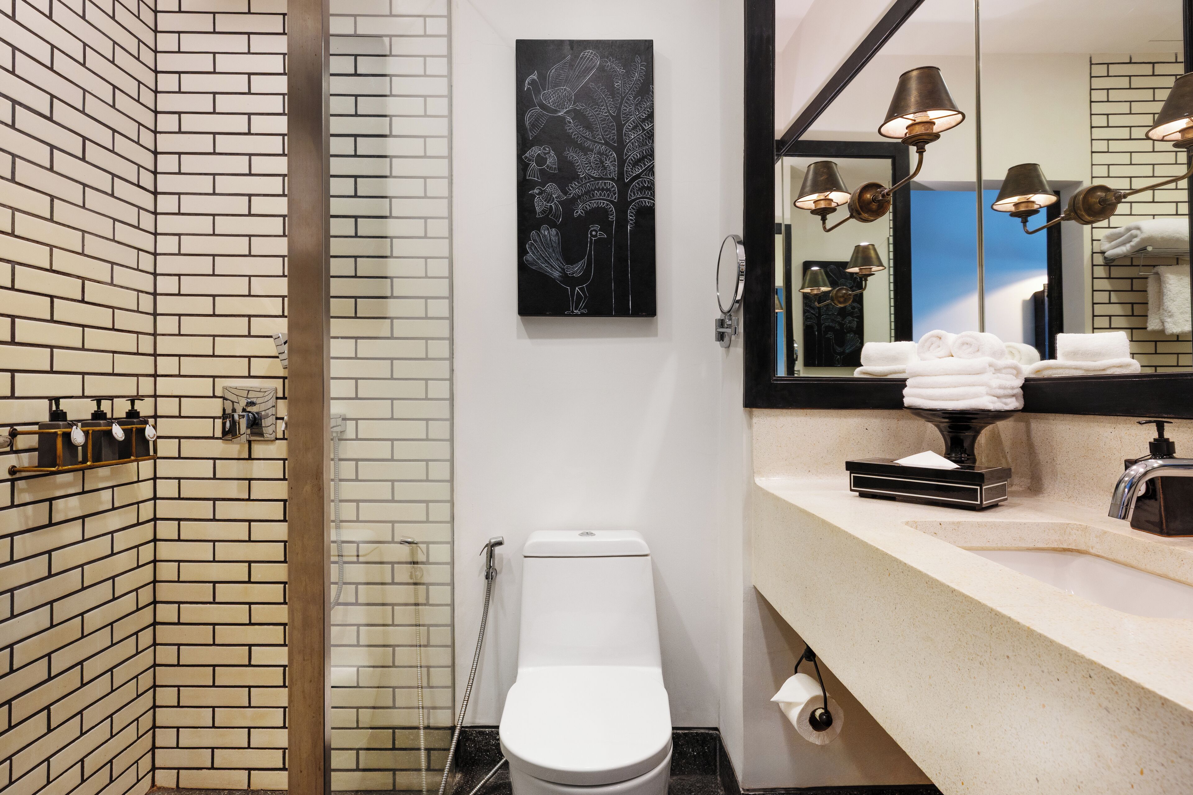 A modern bathroom with a brick wall, a white toilet, a sink with a mirror, and a towel rack.