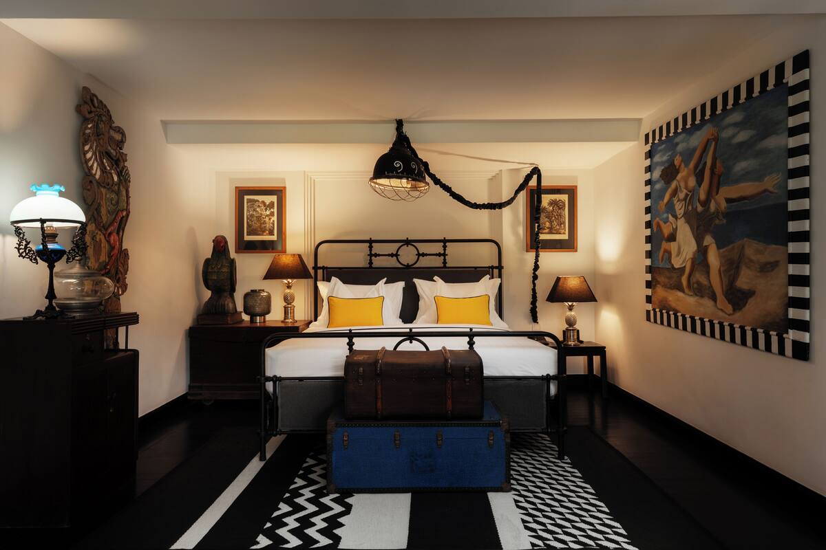A bedroom with a bed, bedside lamps, a dresser, a chest of drawers, and a patterned rug.