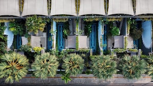 A building facade with multiple balconies, each adorned with lush greenery and patterned blue doors.