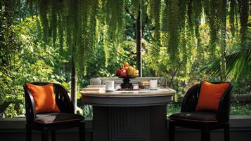 A round table with two chairs, a fruit bowl, and a small clock.