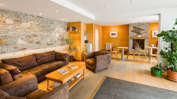 Ein modernes Wohnzimmer mit Steinwand, Holzvertäfelung, Kamin und gemütlicher Sitzecke.