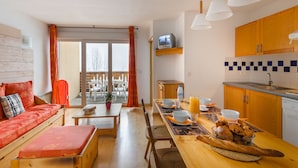 Ein kompakter Wohnbereich mit Sofa, Esstisch und Küchenzeile.