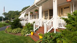 A house with a porch, steps, and hanging flower pots. - Mount Battie Inn (Lincolnville)