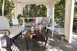 Un área de estar al aire libre cubierta con muebles de mimbre, una mesa de vidrio y una planta en maceta.
