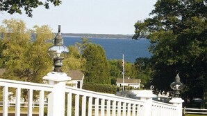 A white fence with a lamp post and a view of a body of water in the background. - Mount Battie Inn (Lincolnville)