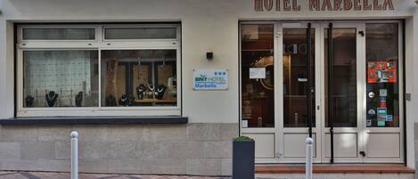 A hotel facade with a sign reading "HOTEL MARBELLA" and a "BRIT HOTEL Marbella Comfort" sign.