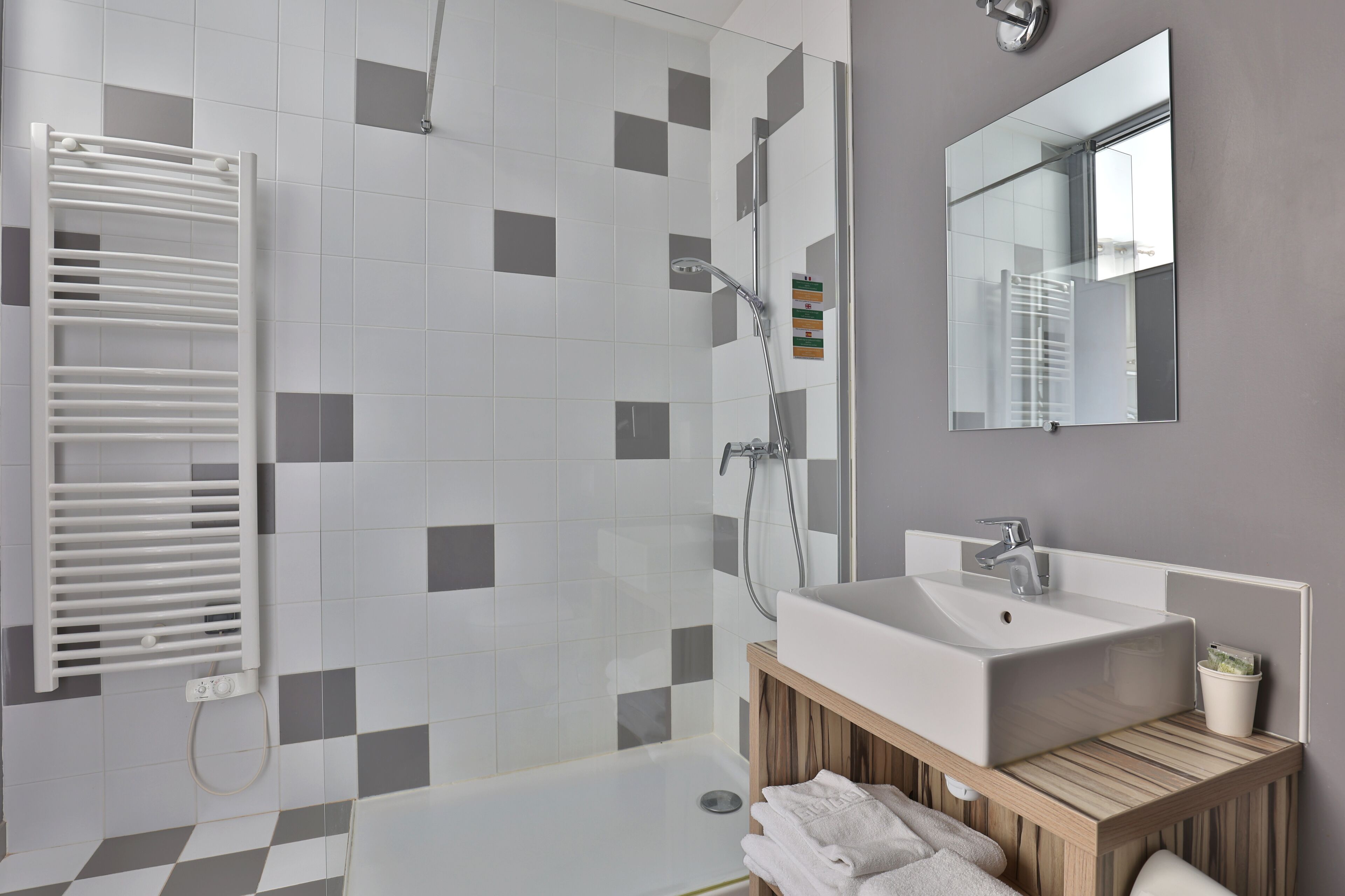 Een moderne badkamer met een douche, wastafel en spiegel.