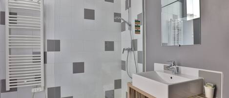 Un baño moderno con ducha, lavabo y espejo.