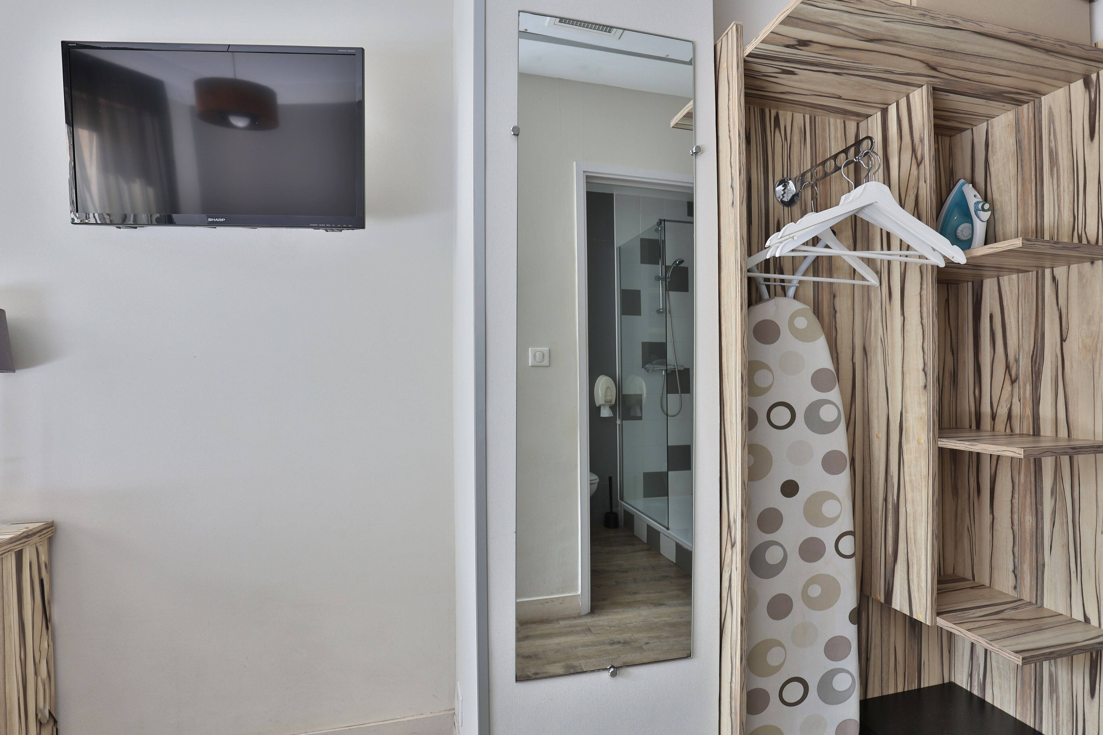 A modern bathroom with a flat-screen TV, a shower, and a wooden vanity with a hanging shower curtain.