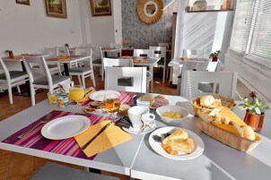 A breakfast setup with plates, cups, and a basket of bread on a table.
