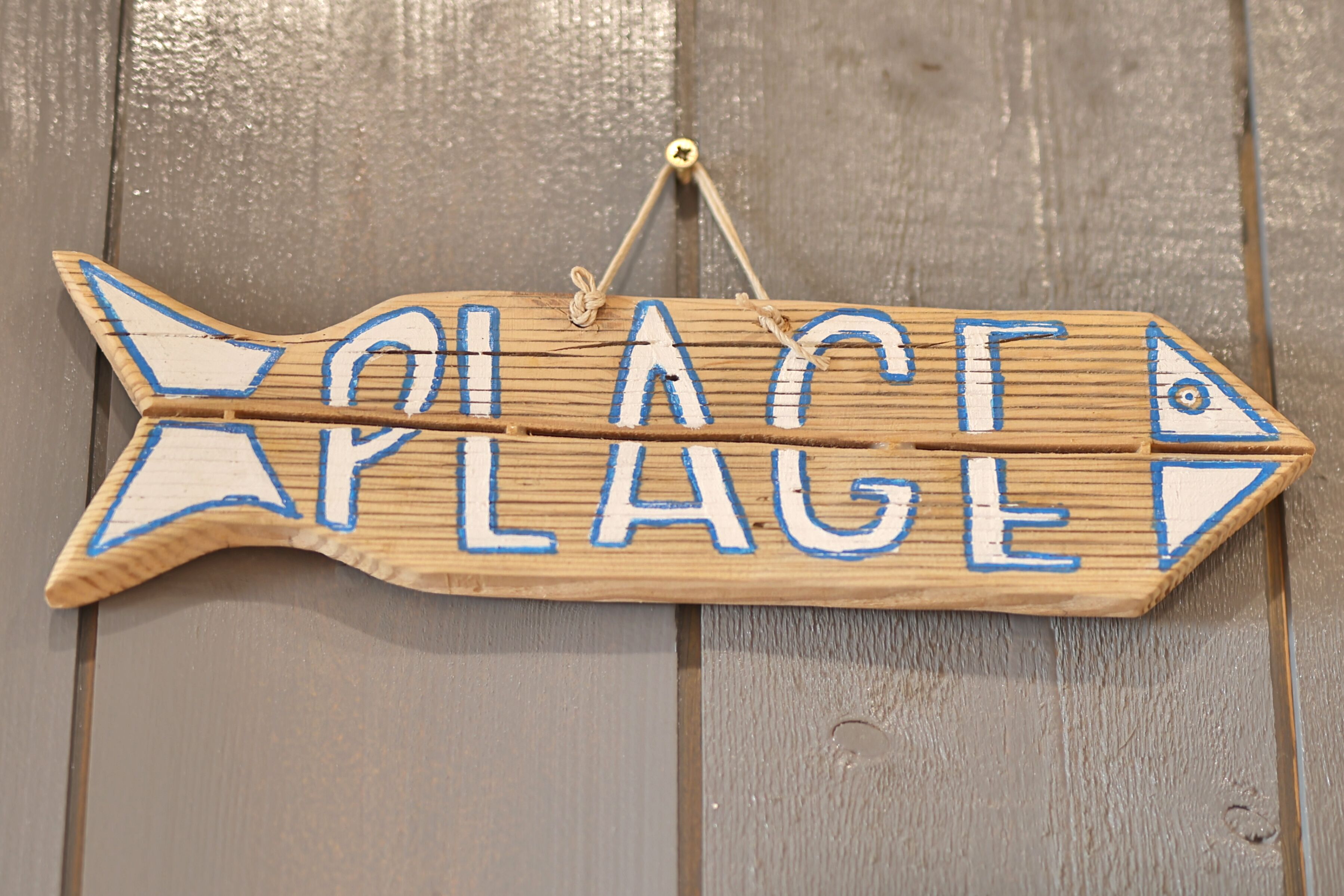 A wooden sign with the words "PLACE PLAGE" and fish shapes.