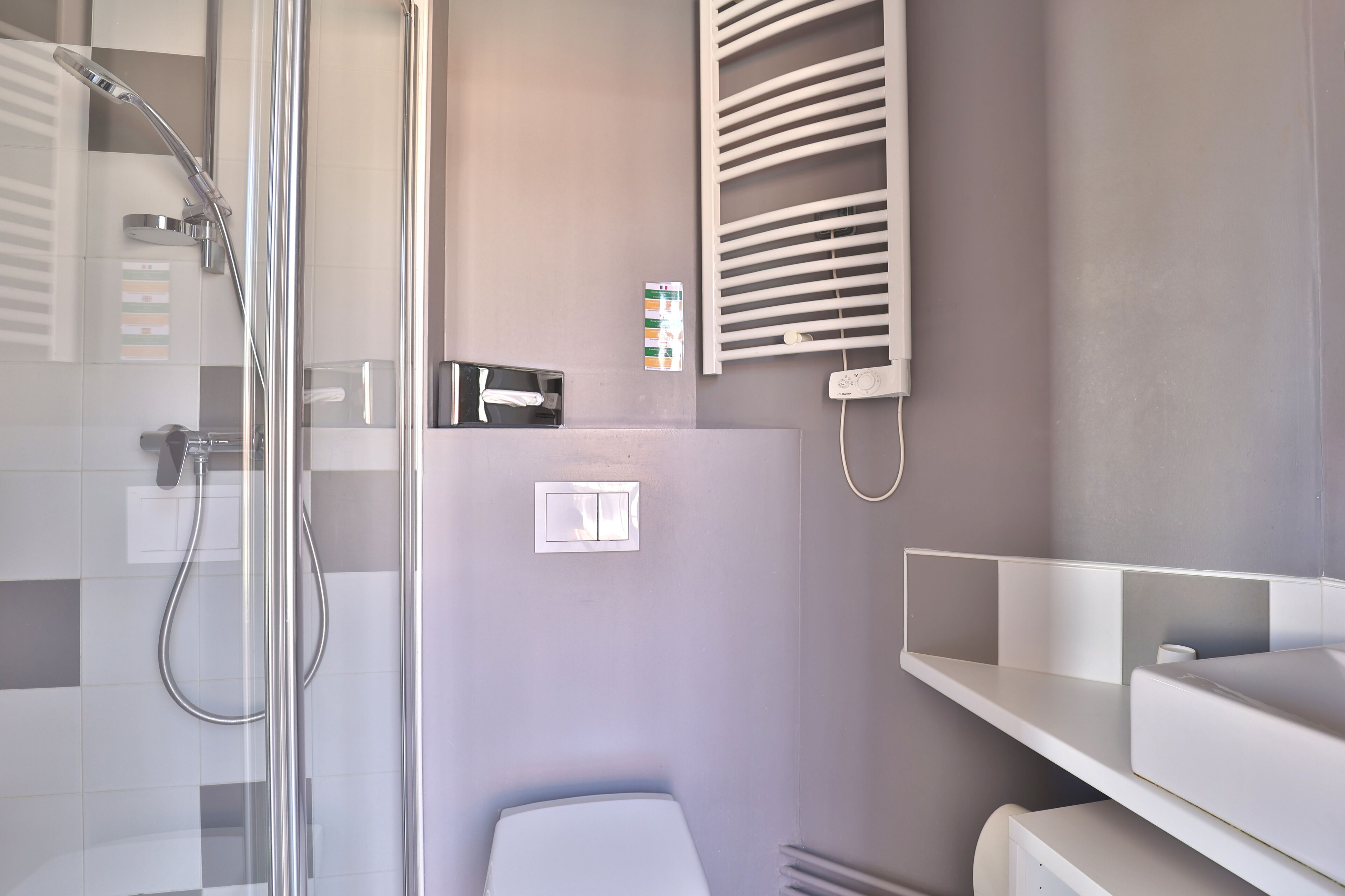 A modern bathroom with a glass-enclosed shower, a toilet, and a towel rack.
