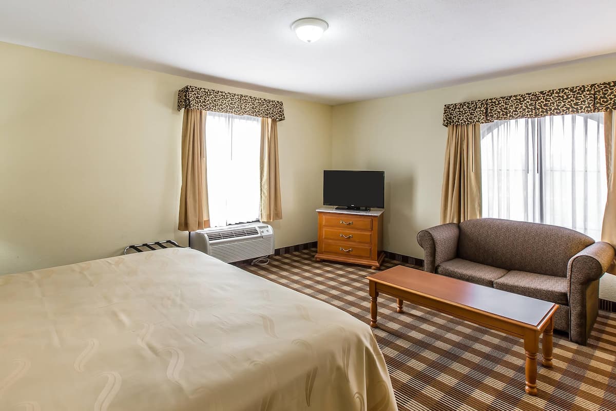 A hotel room with two beds, a television, a sofa, and a small table.